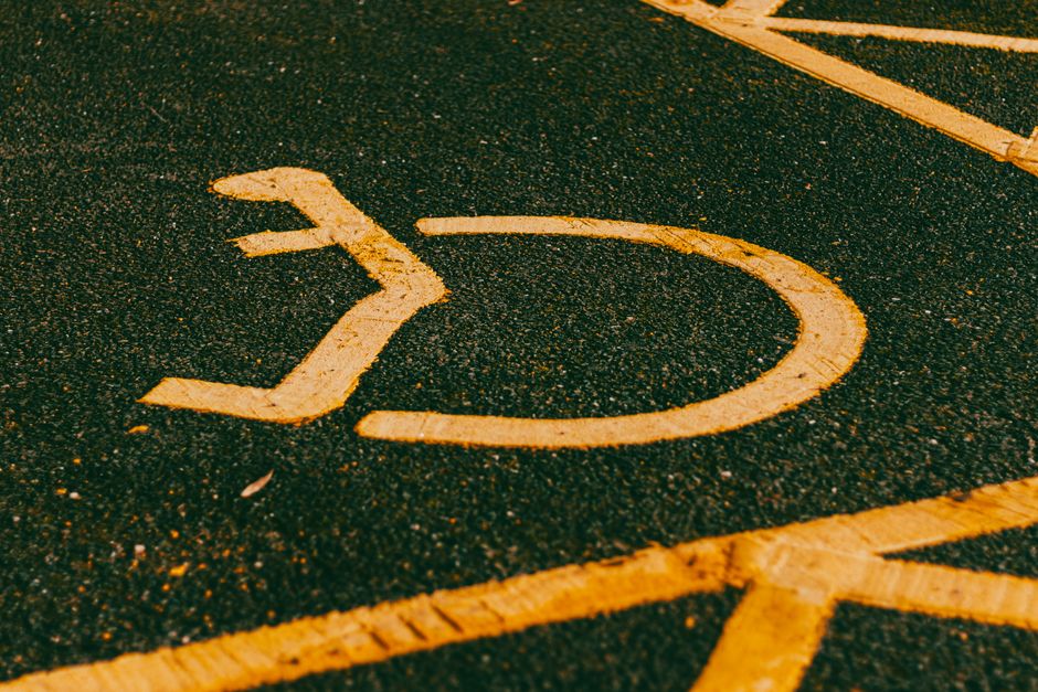 Close-up of an accessibility parking symbol on a dark asphalt surface, painted in yellow.